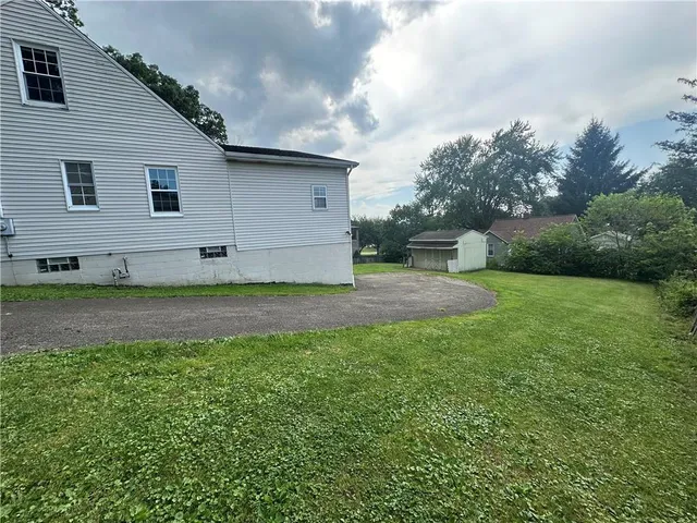 a white house that has a small yard and trees in the background