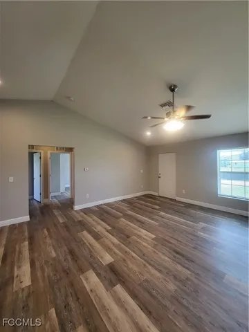 an empty room with wooden floor chandelier and windows