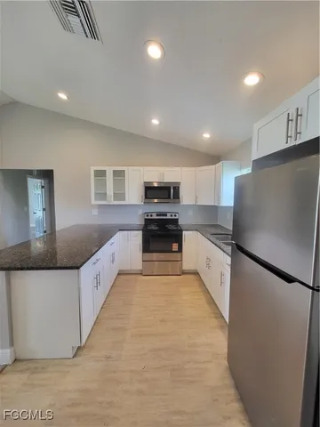 a large kitchen with stainless steel appliances kitchen island granite countertop a refrigerator and a stove top oven