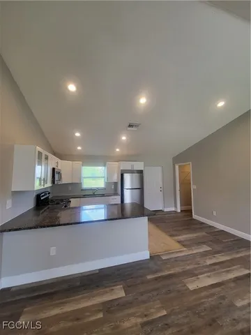 a view of a kitchen with a sink and dishwasher a stove top oven with wooden floor