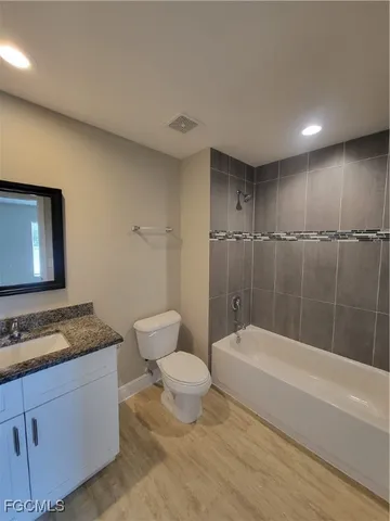 a bathroom with a granite countertop sink a toilet and bathtub