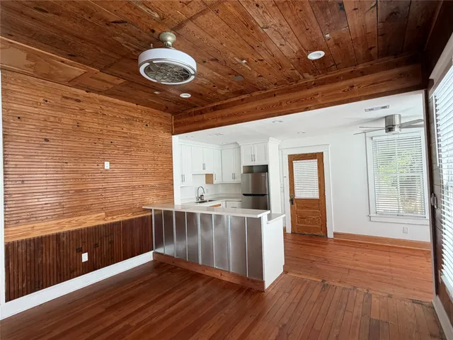 a view of kitchen with stainless steel appliances kitchen island hardwood floor and brick wall