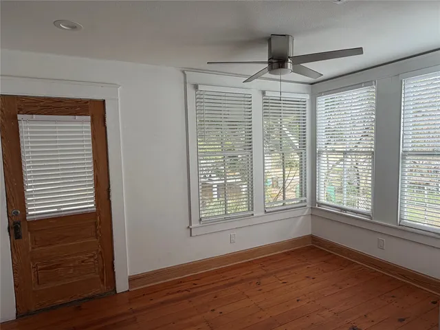 a view of an empty room with wooden floor and a window