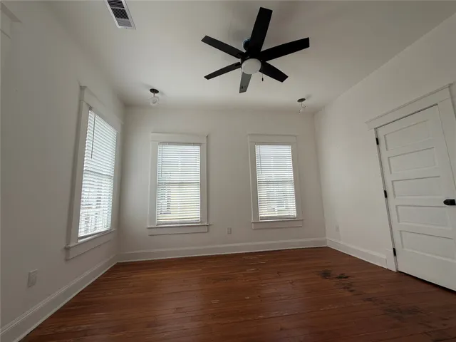 a view of empty room with wooden floor and fan