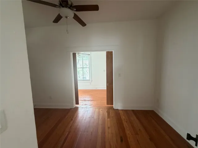 a view of a room with wooden floor a ceiling fan and window