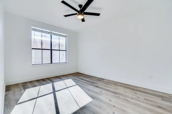 an empty room with wooden floor cabinet and windows