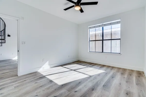 an empty room with wooden floor cabinet and windows