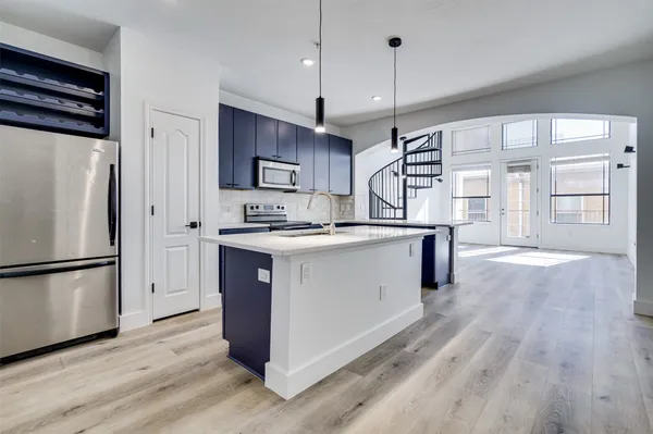 a kitchen with kitchen island a refrigerator a stove a sink and a wooden floor