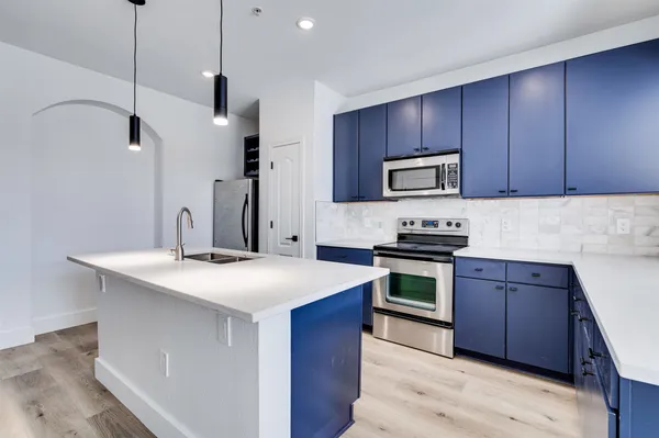 a kitchen with stainless steel appliances kitchen island a wooden floor and a sink