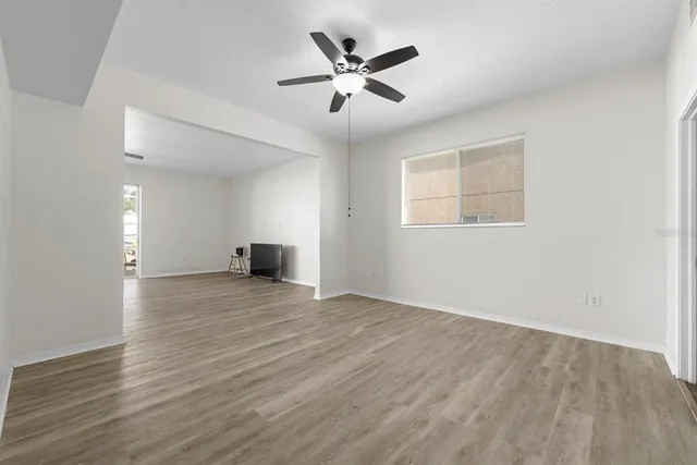 an empty room with wooden floor and ceiling fan