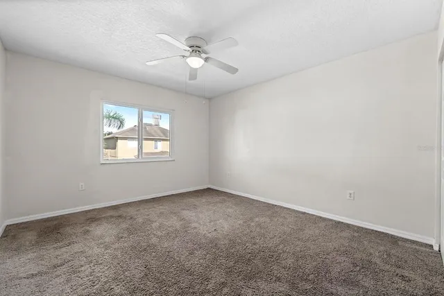 an empty room with a chandelier fan and windows