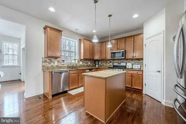 a kitchen with stainless steel appliances granite countertop a refrigerator a stove top oven a sink dishwasher and white cabinets with wooden floor