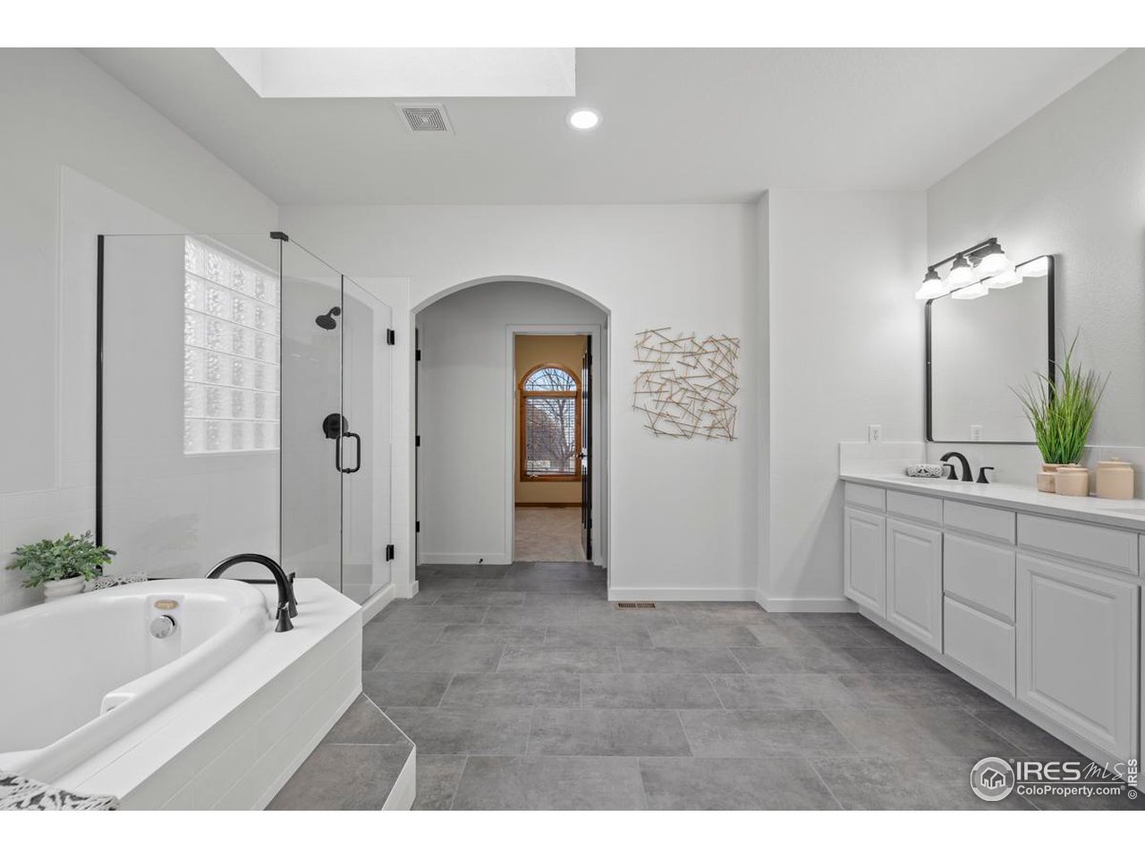 2097 Meander Road Windsor, CO 80550 - Photo 15 of 33 a bathroom with a bathtub a double vanity sink a vanity and a large mirror