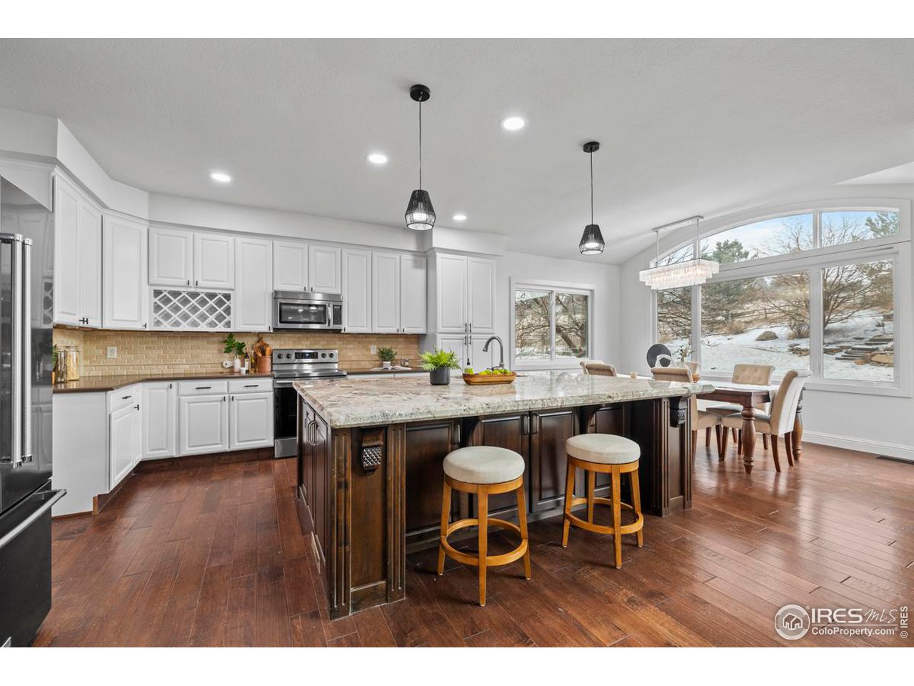 2097 Meander Road Windsor, CO 80550 - Photo 6 of 33 a kitchen with granite countertop a table chairs a sink dishwasher refrigerator and cabinets with wooden floor