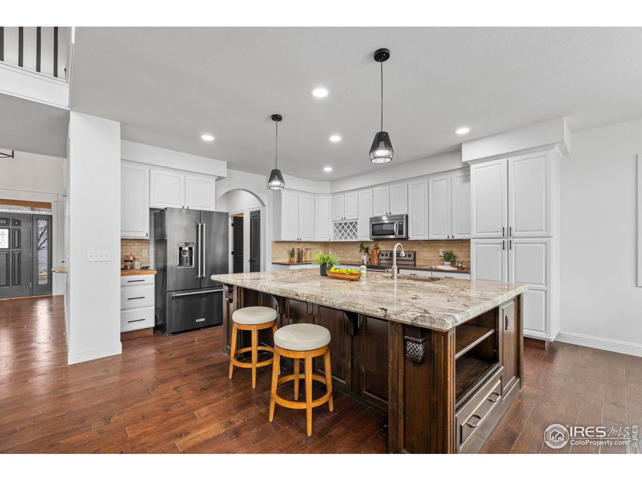 2097 Meander Road Windsor, CO 80550 - Photo 7 of 33 a kitchen with stainless steel appliances kitchen island granite countertop a table chairs sink and cabinets