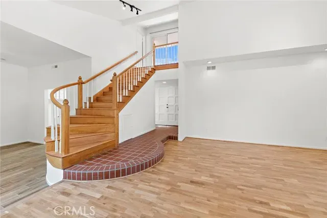 a view of an empty room with wooden floor and stairs