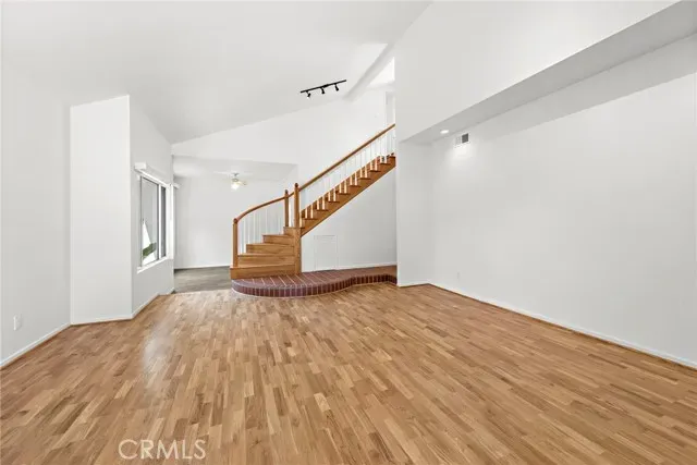 a view of an empty room with wooden floor fireplace and a window