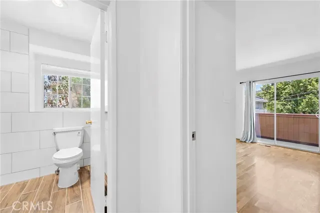 a view of an empty room with wooden floor fireplace and a window