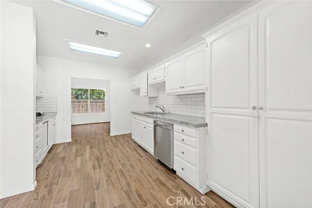 a kitchen with granite countertop cabinets stainless steel appliances a sink and wooden floor