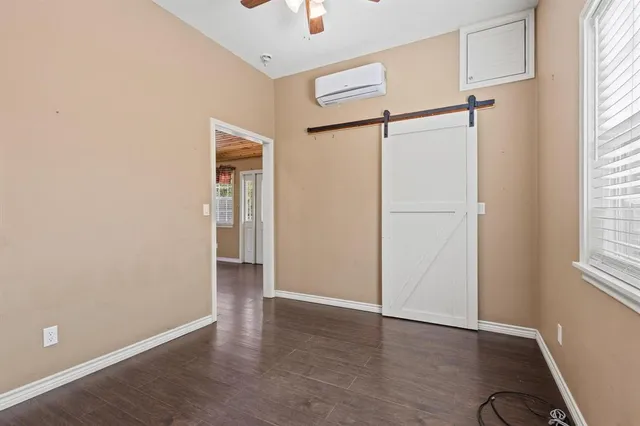 an empty room with wooden floor closet and windows