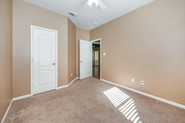 a view of an empty room and chandelier fan