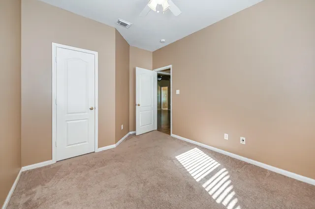 a view of an empty room and chandelier fan
