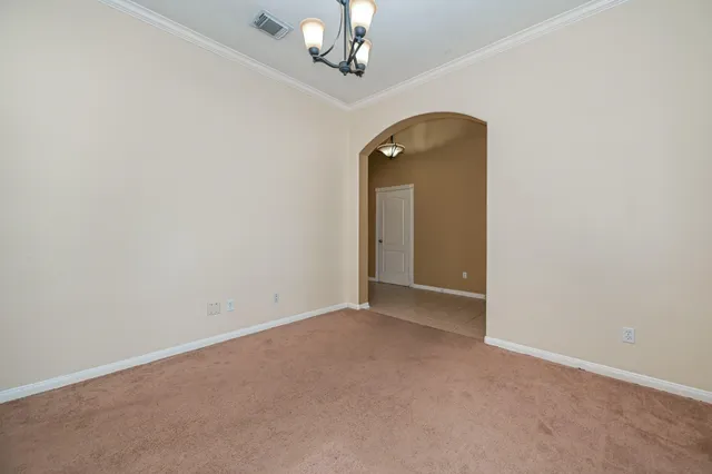 an empty room that has a chandelier fan