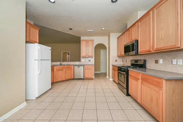 a large kitchen with stainless steel appliances kitchen island granite countertop a refrigerator a stove top oven a sink and dishwasher