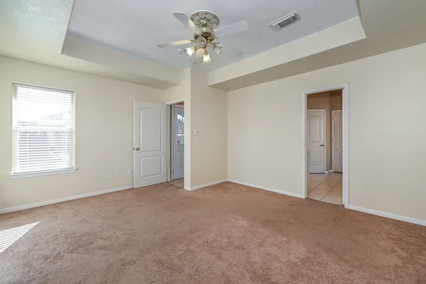 an empty room with a chandelier fan and windows