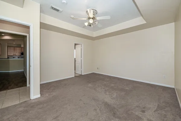 an empty room with a chandelier fan and windows