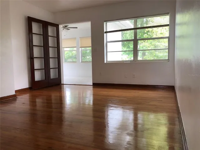 a view of empty room with wooden floor and fan