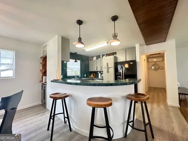 a kitchen with stainless steel appliances granite countertop white cabinets and chairs