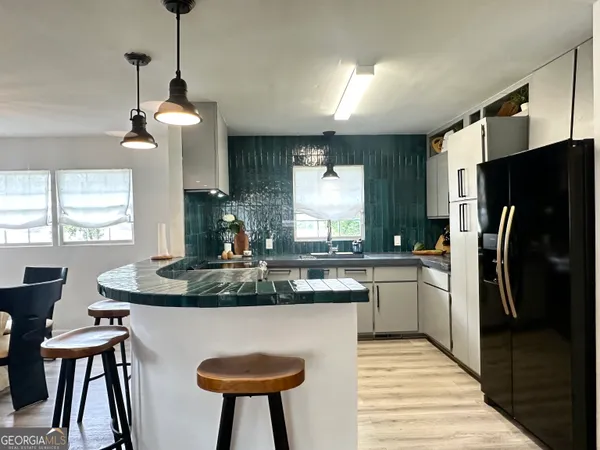 a kitchen with stainless steel appliances granite countertop a refrigerator a sink a stove a dining table and chairs