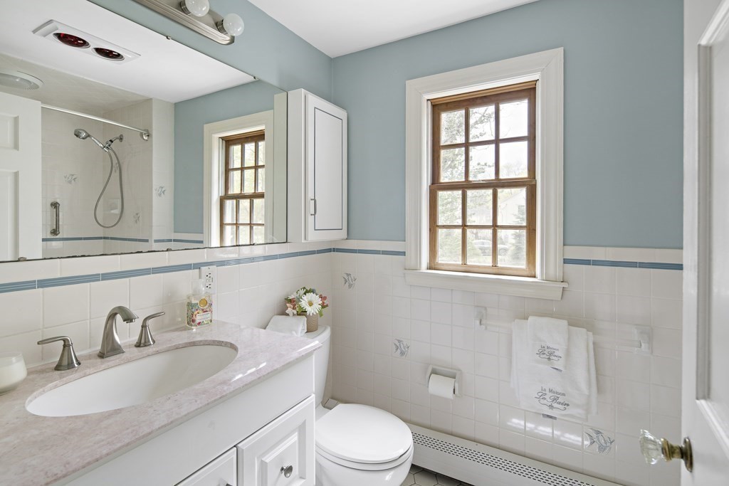 7 Perkins Road Winchester, MA 01890 - Photo 23 of 38 a bathroom with a granite countertop toilet a sink a mirror and a window