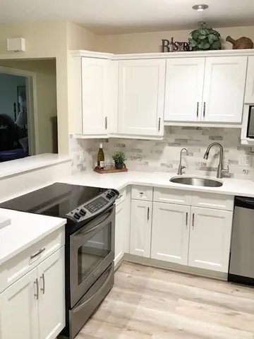 a kitchen with white cabinets and appliances