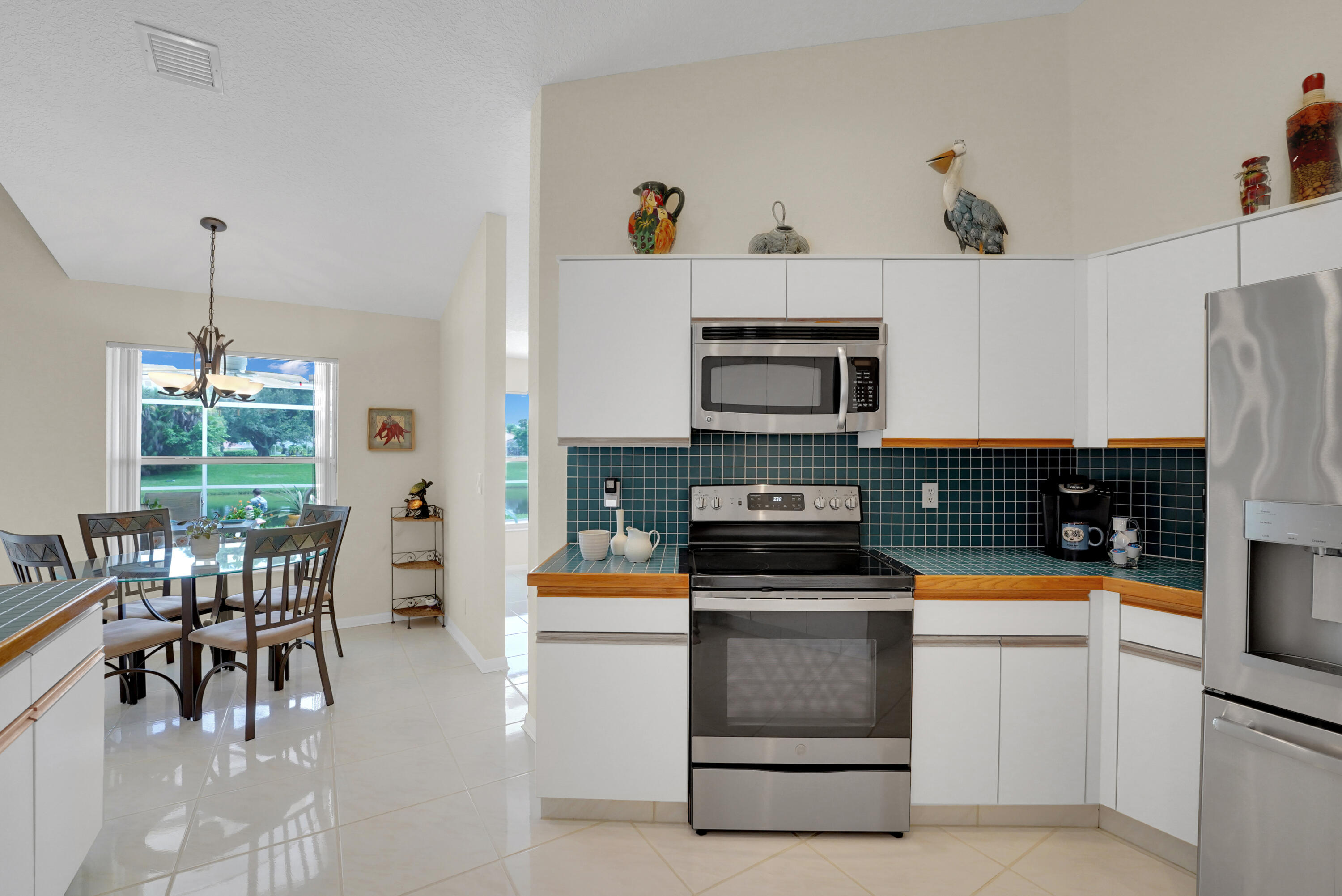 22331 Kettle Creek Way Boca Raton, FL 33428 - Photo 35 of 86 a kitchen with stainless steel appliances a stove a sink a microwave a dining table and chairs