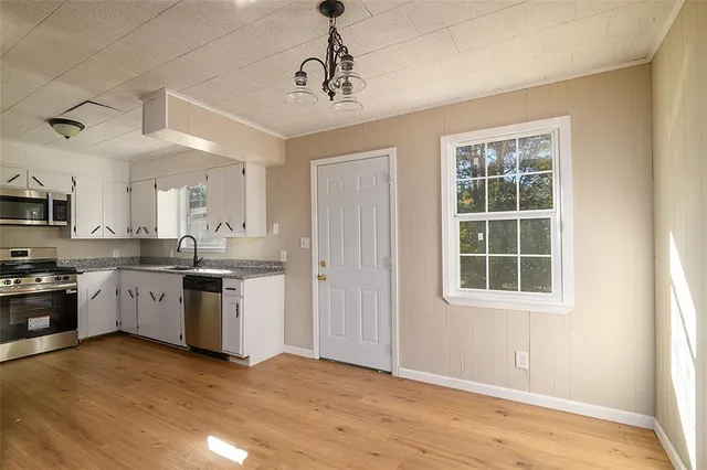 a large kitchen with cabinets wooden floor and stainless steel appliances