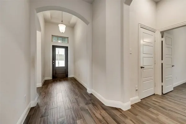 an empty room with wooden floor mirror and windows