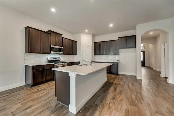 a large kitchen with stainless steel appliances granite countertop a large stove a sink dishwasher and a refrigerator with wooden floor