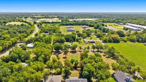 an aerial view of residential houses with outdoor space and trees all around