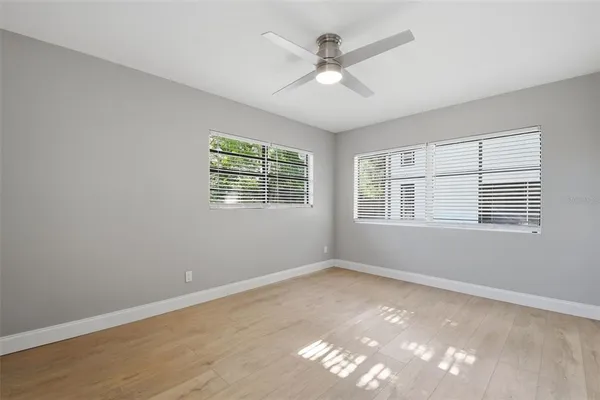 a view of empty room with wooden floor and fan