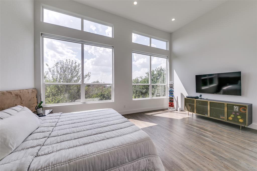 2908 Raleigh Street, Unit 204 Dallas, TX 75219 - Photo 21 of 25 a bedroom with a large bed and a flat tv screen on dresser