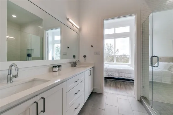 a spacious bathroom with a double vanity sink a mirror and next to a window
