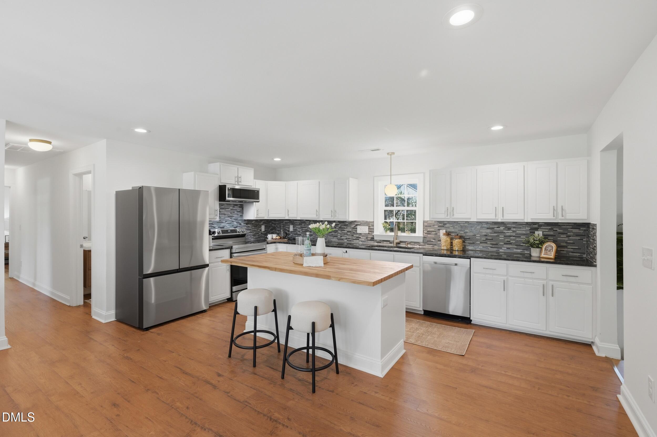 2301 Milburnie Road Raleigh, NC 27610 - Photo 4 of 23 a kitchen with stainless steel appliances granite countertop a refrigerator a sink dishwasher a stove and white cabinets with wooden floor