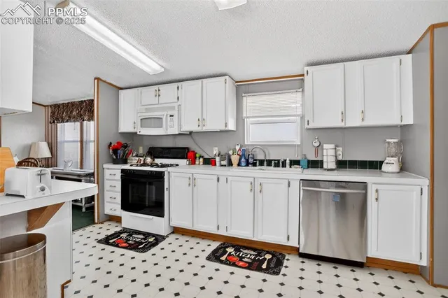 a kitchen with granite countertop a sink stove and white cabinets