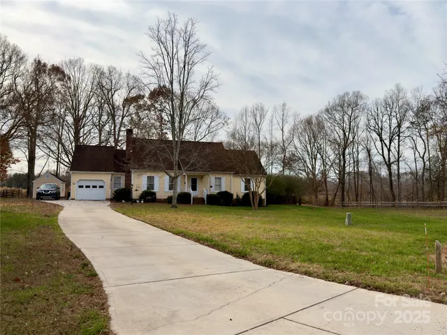 a view of a house with a yard and large trees