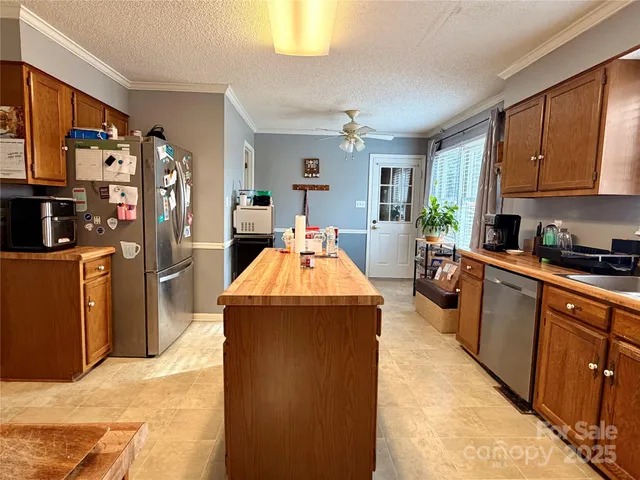 a very nice looking open kitchen with stainless steel appliances granite countertop a stove refrigerator and a refrigerator with wooden floor