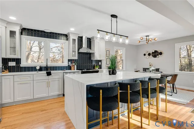 a kitchen with stainless steel appliances kitchen island granite countertop a table chairs sink and cabinets