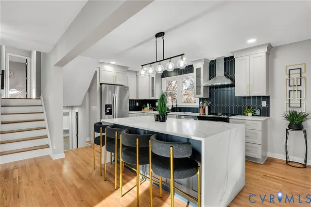 a kitchen with stainless steel appliances kitchen island granite countertop a table chairs in it and wooden floors