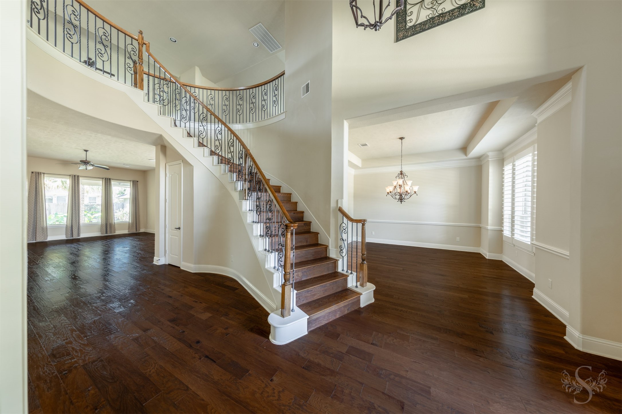 5803 Mustang Ridge Lane Fulshear, TX 77441 - Photo 7 of 48 Grand 2 story entry showcases rich wood flooring, soaring ceilings and a sweeping curved staircase with decorative iron balusters that creates a stunning first impression. Plantation shutters, crown molding and elegant architectural details add warmth and character throughout the home.